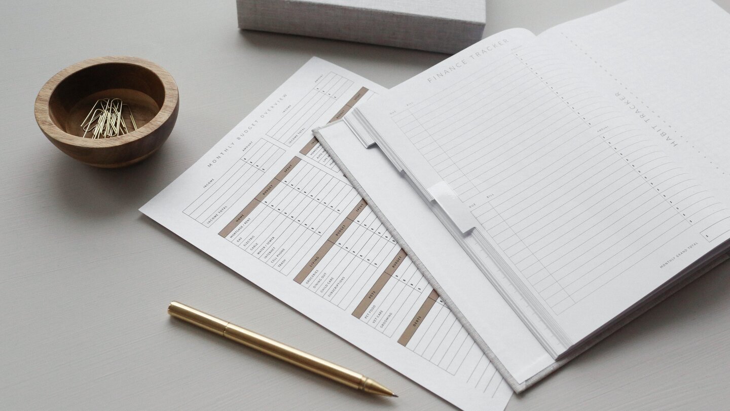 Image of papers with table for budget, a pen and some paper clips on a desk